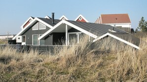 Une maison moderne avec un toit en pente, de grandes fenêtres et une cheminée.