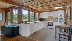 Eine moderne Küche mit Holzbalken, weißen Schränken und einer großen Kochinsel.