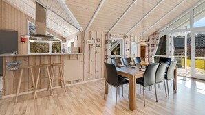 A modern kitchen with a wooden ceiling, a dining area with a table and chairs, and a bar area with stools. - "Germaine" - 1.2km from the sea by Interhome (Fanø)