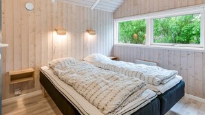 A bedroom with two beds, wooden walls, a window with a view of greenery, and wall-mounted lights. - "Germaine" - 1.2km from the sea by Interhome (Fanø)
