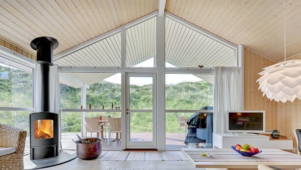 Un salon moderne doté d’un poêle à bois, de grandes fenêtres et offrant une vue sur l’extérieur.