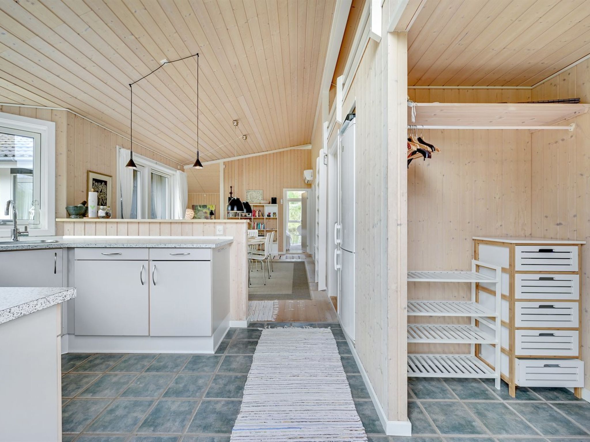 A modern kitchen with white cabinets, a granite countertop, and a wooden ceiling.