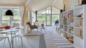 Une pièce spacieuse comprenant un coin repas, une bibliothèque et donnant sur l’extérieur.