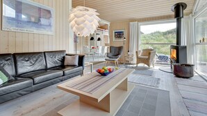 Un salon moderne avec un canapé en cuir, une table basse en bois et une grande fenêtre donnant sur un paysage magnifique.