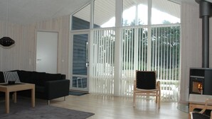 A spacious living room with a large sliding glass door leading to a balcony, a fireplace, and a modern black sofa. - "Tero" - 450m from the sea by Interhome (Vejers Strand)