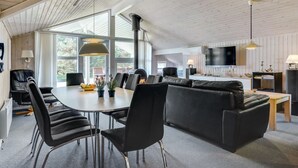 A modern living room with a fireplace, a dining area, and a TV mounted on the wall.
