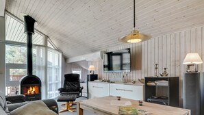 A cozy living room with a fireplace, leather sofa, wooden coffee table, and a TV mounted on the wall.