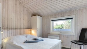 A bedroom with a bed, a window, a chair, and a wardrobe.