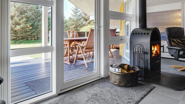 A modern interior with a wood-burning stove, a dining area with outdoor views, and a cozy seating area.