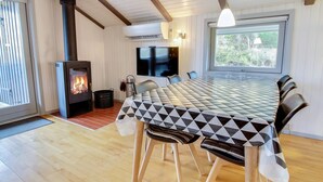 A cozy room with a fireplace, a dining table with chairs, a TV, and a window with a view. - "Igilfar" - 700m from the sea by Interhome (Vejers Strand)