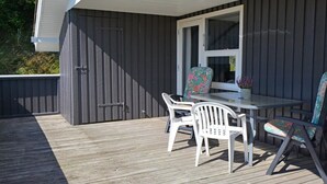 A covered outdoor deck with a table and chairs, a window, and a door. - "Igilfar" - 700m from the sea by Interhome (Vejers Strand)