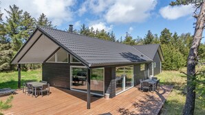 A modern cabin with a large deck, outdoor seating, and a glass enclosure for the main living area. - "Delan" - 1.3km from the sea by Interhome (Vejers Strand)