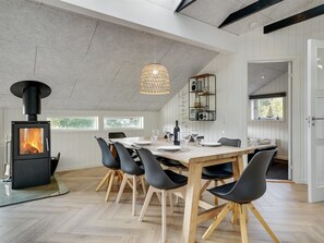 Un comedor moderno con chimenea de leña, una mesa grande y sillas negras.