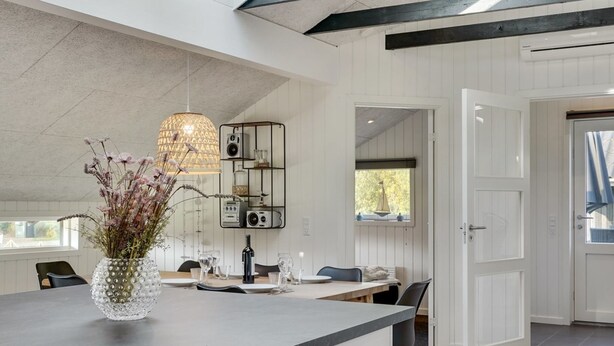 A modern kitchen with a marble countertop, a glass vase with flowers, and a pendant light.