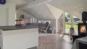 A modern interior with a kitchen area, a seating area with a fireplace, and a view of the outdoors.