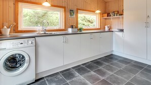 Una cocina moderna con paredes de madera, dos ventanas, una lavadora y un fregadero.