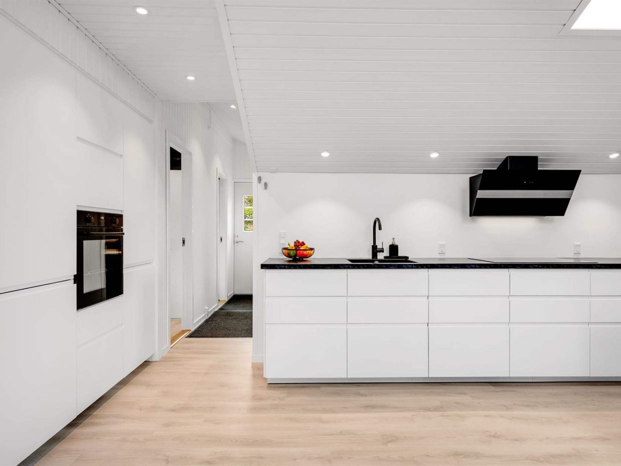 Une cuisine moderne avec des meubles blancs, un plan de travail noir et un four encastré.