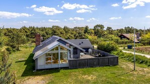 Ein modernes Haus mit Satteldach, großen Fenstern und einer Terrassenfläche.