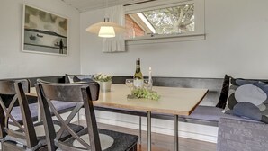 A dining area with a wooden table, chairs, a bench, and a pendant light.