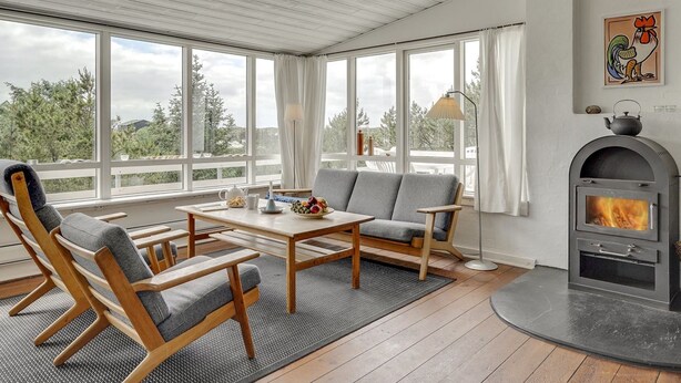 A cozy living room with a fireplace, large windows, and a view of the outdoors.