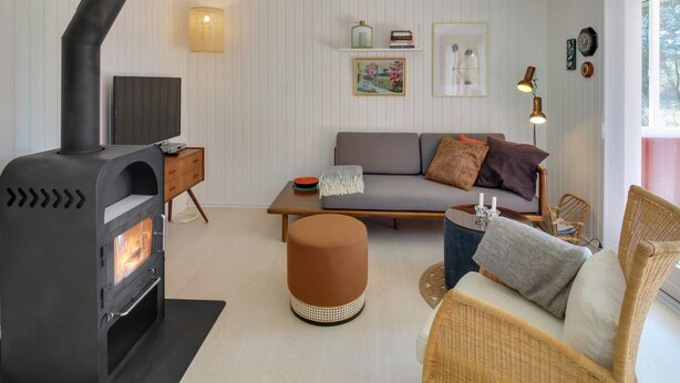 A cozy living room with a modern fireplace, a sofa, a coffee table, and a wicker chair. - "Aulikki" - 900m from the sea by Interhome (Vejers Strand)