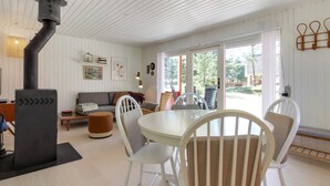 A cozy living room with a fireplace, a dining area with white chairs, and a sofa with cushions. - "Aulikki" - 900m from the sea by Interhome (Vejers Strand)
