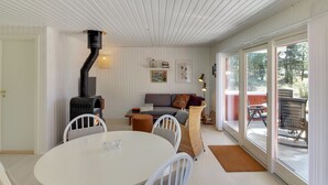 A cozy living room with a fireplace, a dining area with a round table, and a sofa. - "Aulikki" - 900m from the sea by Interhome (Vejers Strand)