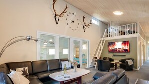 A modern living room with a sectional sofa, a coffee table, a fireplace, and a TV mounted on the wall.