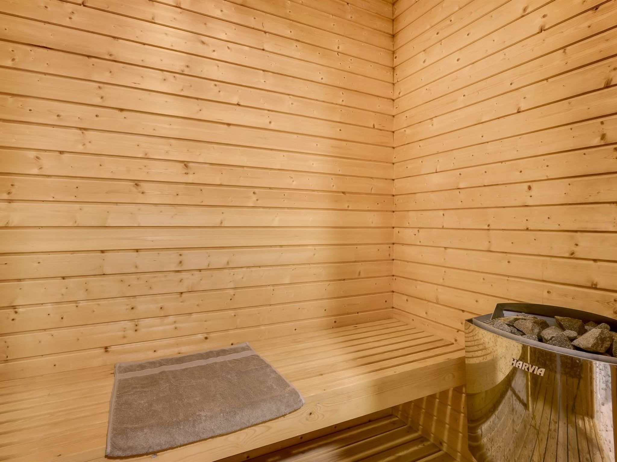 Un sauna en bois, doté d’un banc et d’un récipient rempli de pierres, probablement utilisé pour le chauffage.
