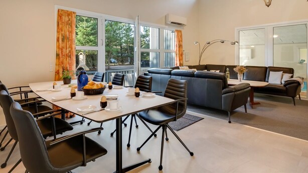 A modern interior with a dining area, sofa, and a wall-mounted deer skull.