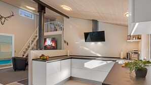 A modern kitchen with white cabinetry, a built-in stove, and a flat-screen TV.