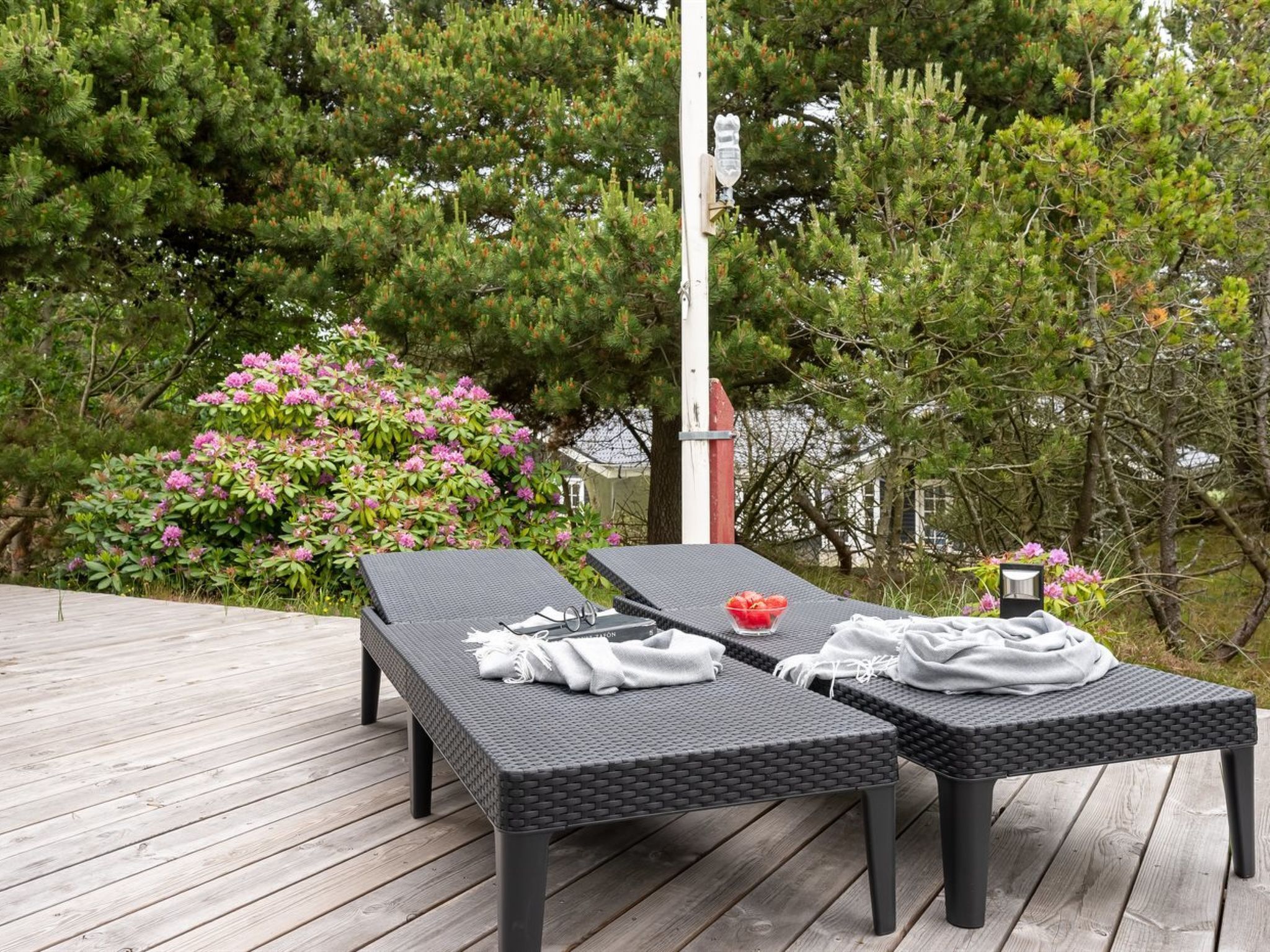 Une terrasse extérieure avec deux chaises longues, une table et un banc.