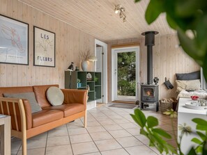 Un salon chaleureux avec un canapé en cuir, une cheminée et une vue sur l’extérieur.