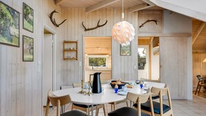 A dining area with a round table, chairs, and a hanging light fixture.