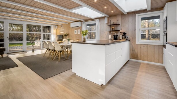 Una cocina moderna con una isla central, ventanas amplias y un área de comedor con luz natural.
