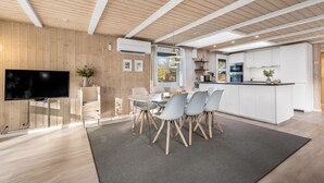 Una cocina moderna con armarios blancos, una isla central y un área de comedor con una mesa redonda y sillas.