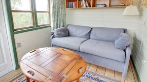 Un salon chaleureux avec un canapé gris, une table basse en bois et une bibliothèque remplie de livres.