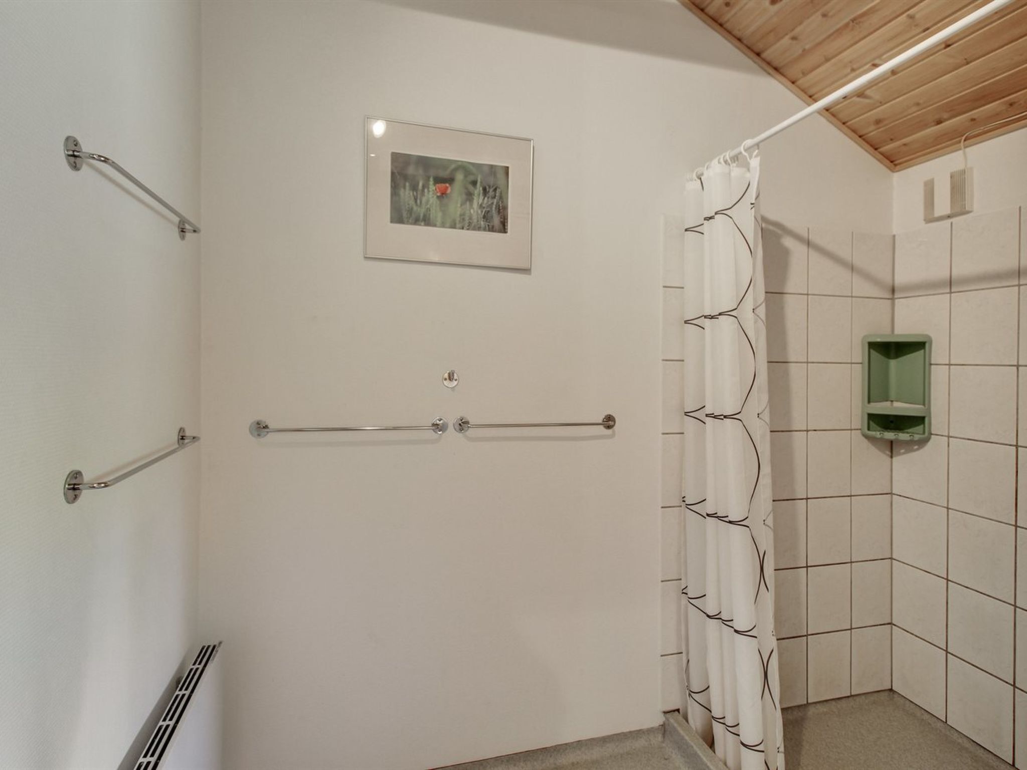 A bathroom with a shower, towel bars, a picture on the wall, and a green soap dispenser.