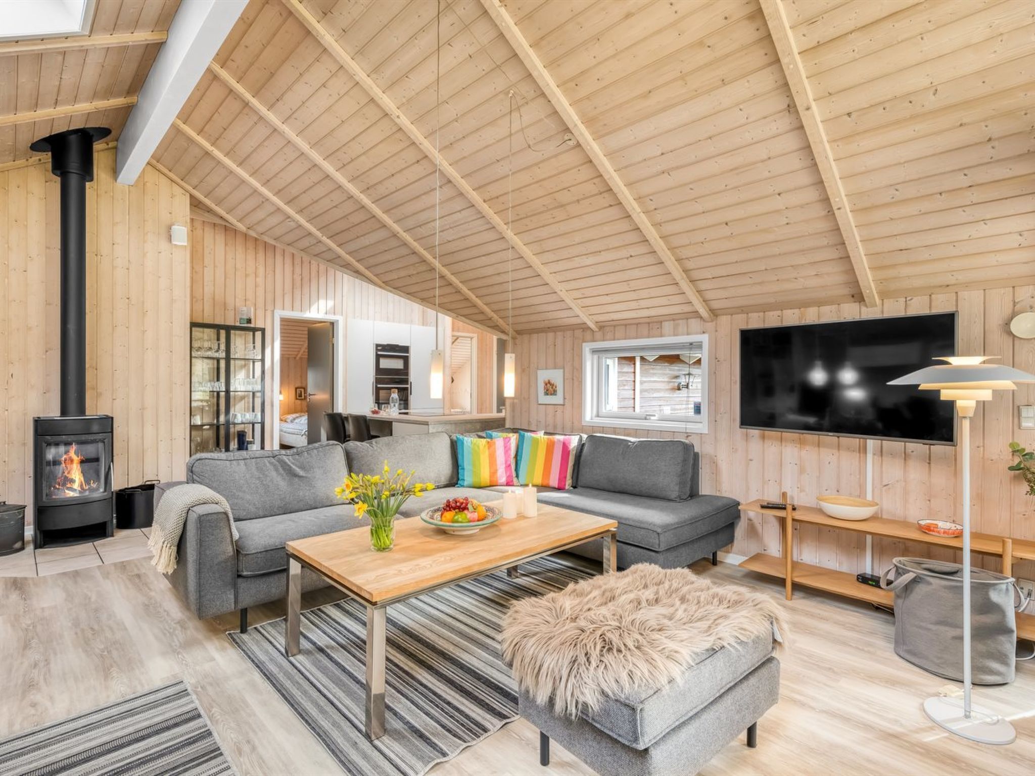 A cozy living room with a sofa, ottoman, and a TV mounted on the wall.