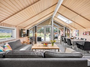 A spacious interior with a high ceiling, a cozy seating area, a dining table, and a view through large windows. - "Anisette" - 1km from the sea by Interhome (Vejers Strand)