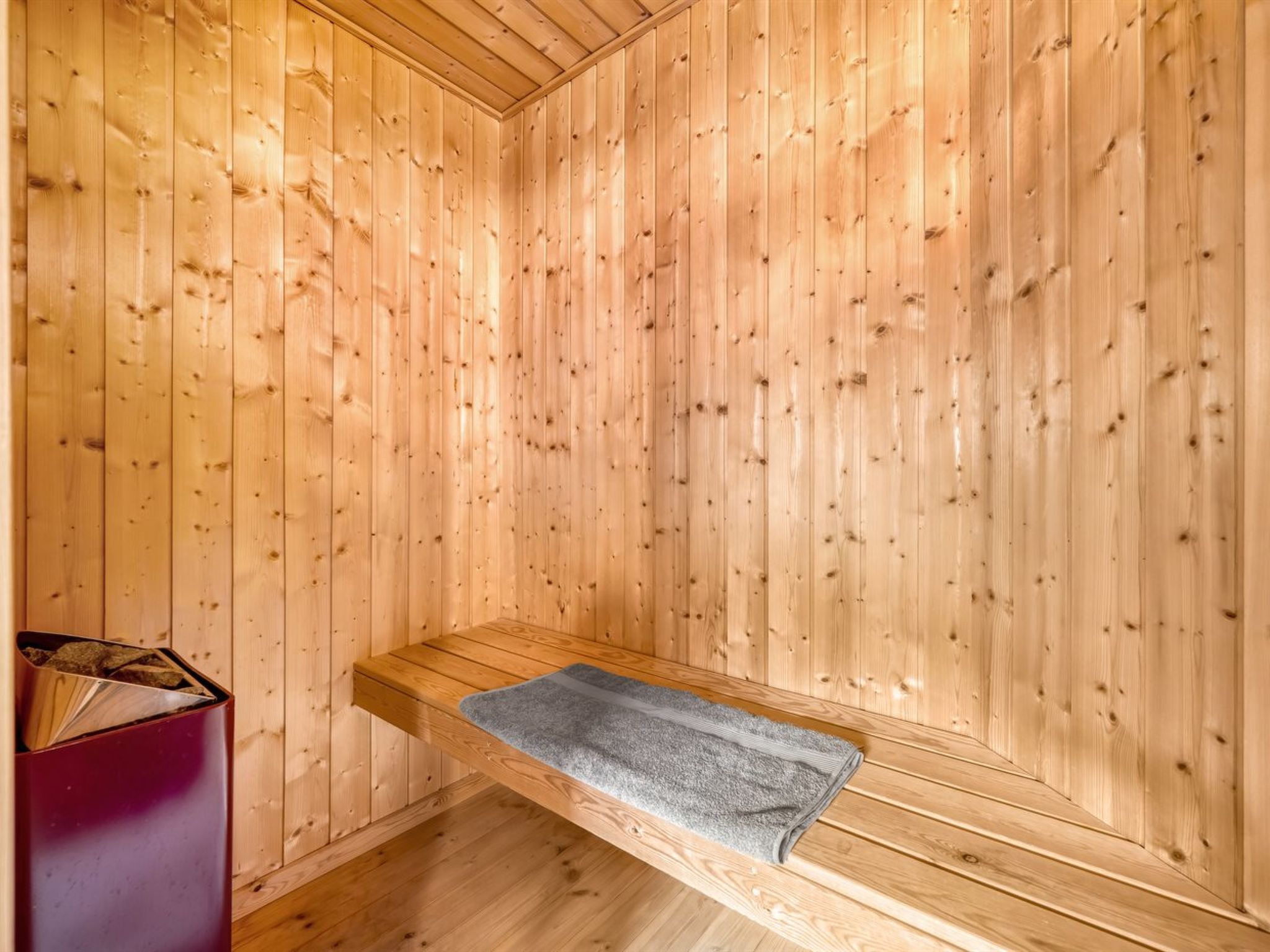 A sauna room with wooden walls and a bench.