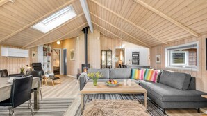 Um amplo loft com pé direito alto, área de jantar, conjunto de sofás e cozinha.