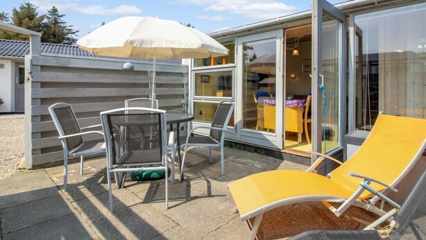 A patio with a table and chairs, a yellow lounge chair, and a white umbrella. - "Genadij" - 1km from the sea by Interhome (Vejers Strand)