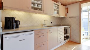 A kitchen with light pink cabinets, a white dishwasher, and a coffee maker on the counter. - "Genadij" - 1km from the sea by Interhome (Vejers Strand)