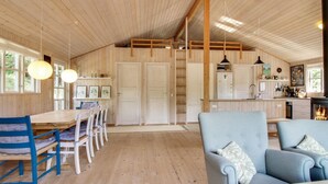 Una habitación amplia con piso de madera, una mesa de comedor con sillas, un sofá y un área de cocina con estufa y refrigerador.