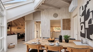 A modern kitchen with wooden cabinets, a dining area with a large table and chairs, and a skylight above. - "Kenny" - 1.2km from the sea by Interhome (Vejers Strand)