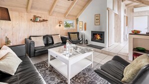 A cozy living room with a fireplace, wooden beams, and a black leather sofa. - "Kenny" - 1.2km from the sea by Interhome (Vejers Strand)