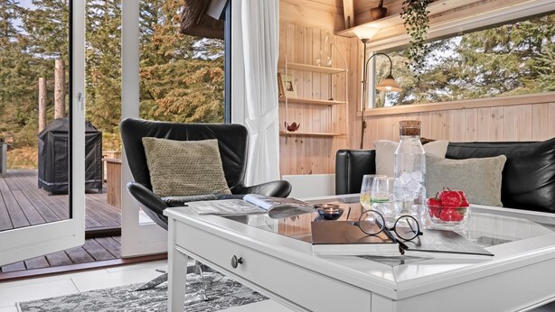 A cozy outdoor seating area with a glass-top table, a black leather chair, and a white side table. - "Kenny" - 1.2km from the sea by Interhome (Vejers Strand)