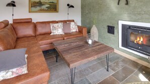 A living room with a leather sofa, a wooden coffee table, a fireplace, and a painting on the wall. - "Lioba" - 400m from the sea by Interhome (Vejers Strand)