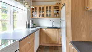 A modern kitchen with wooden cabinets, a built-in dishwasher, and a large window providing natural light. - "Lioba" - 400m from the sea by Interhome (Vejers Strand)